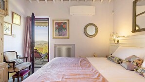 A bedroom with a bed, a chair, a dresser, a radiator, a mirror, and a window with a view. - Villanova sul Molino Lonciano with Private Pool, Wi-Fi, and Air Conditioning (Sesto Fiorentino)