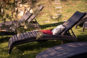 Poltrone da esterno con una coperta rossa e un bicchiere di vino rosso.