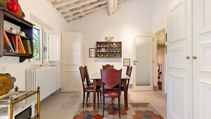A dining area with a hexagonal patterned floor, a table with chairs, a bookshelf, and a radiator. - Villanova sul Molino Lonciano with Private Pool, Wi-Fi, and Air Conditioning (Sesto Fiorentino)