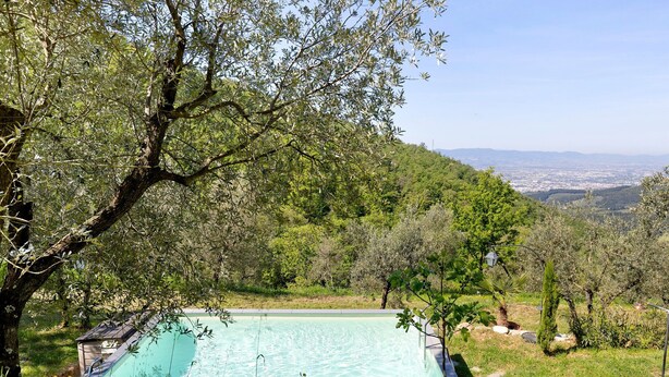 A swimming pool surrounded by trees and a view of a distant city. - Villanova sul Molino Lonciano with Private Pool, Wi-Fi, and Air Conditioning (Sesto Fiorentino)