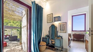 A room with a large sliding glass door, a mirror, a small table, and a wicker basket. - Villanova sul Molino Lonciano with Private Pool, Wi-Fi, and Air Conditioning (Sesto Fiorentino)