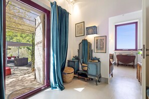 Ein Zimmer mit einer großen Schiebeglasdoor, einem Spiegel, einem kleinen Tisch und einem Korbwäscheschrank.