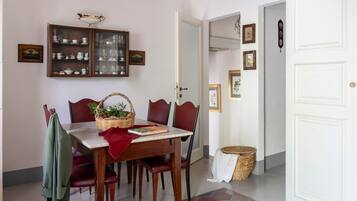 Un comedor con una mesa de madera, sillas tapizadas en rojo, una cesta de mimbre con frutas y un libro.