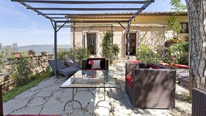 An outdoor patio with wicker furniture, a glass table, and a pergola structure. - Villanova sul Molino Lonciano with Private Pool, Wi-Fi, and Air Conditioning (Sesto Fiorentino)