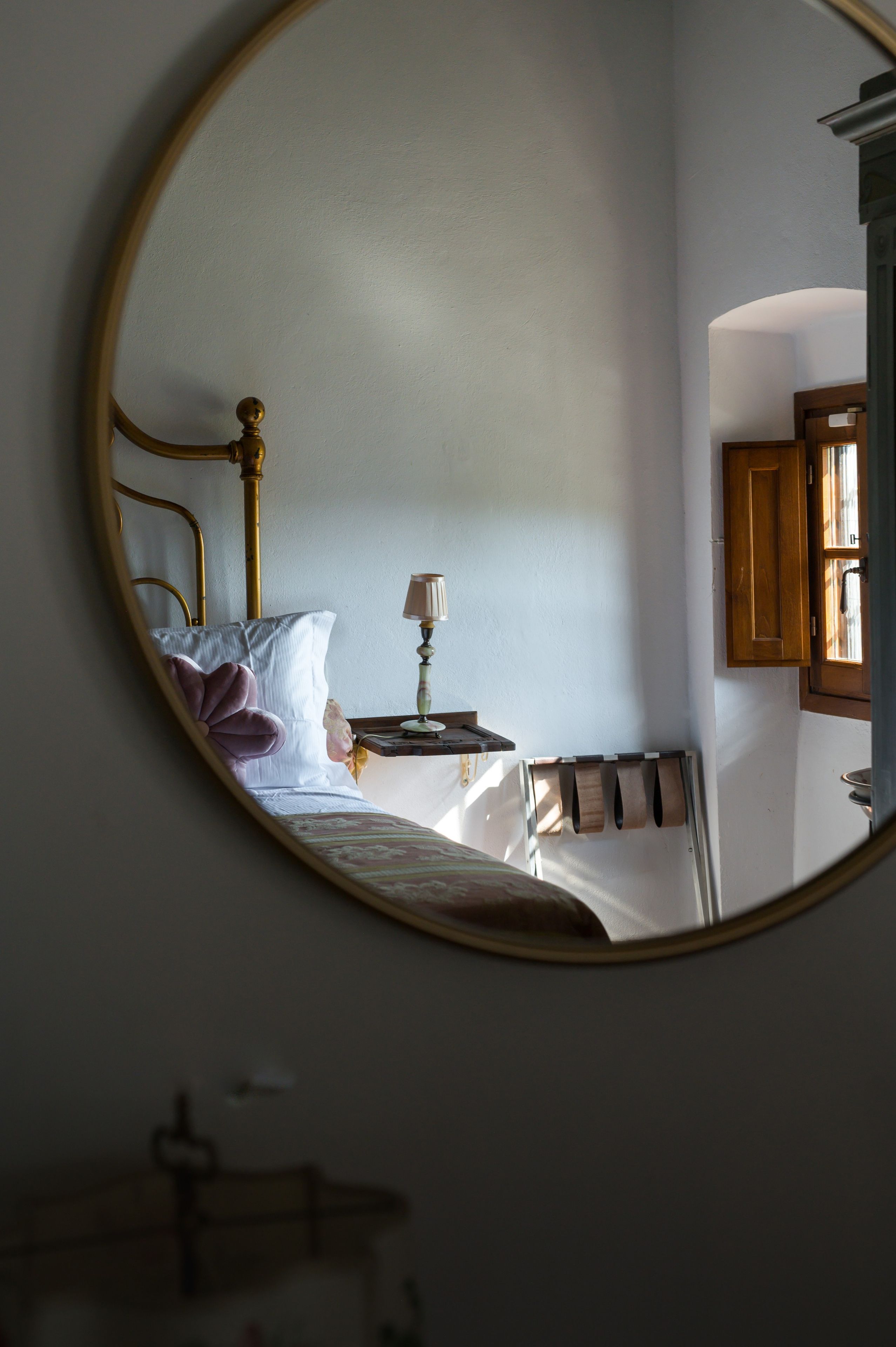 Une chambre à coucher avec un lit, une table de chevet avec une lampe et un miroir au mur.