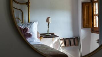 Une chambre à coucher avec un lit, une table de chevet avec une lampe et un miroir au mur.