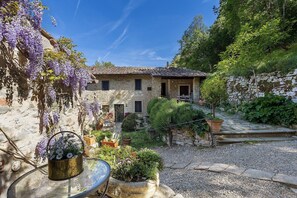 Ein Steinhaus mit Garten, einem Kiesweg und einem Glastisch mit Blumentopf.