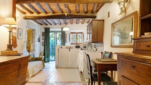 Una camera tradizionale con un letto, mobili in legno, un tavolo da pranzo e un angolo cottura con un fornello.