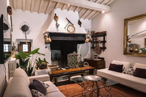 Una sala de estar acogedora con chimenea, un sofá, una mesa de centro y varios objetos decorativos.