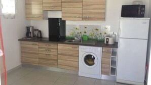 A modern kitchen with wooden cabinets, a washing machine, a refrigerator, and a microwave. - Rental apartment T2, 53m2 à Corte in quiet residence (Corte)