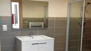 A bathroom with a white sink, a mirror, and a glass-enclosed shower. - Rental apartment T2, 53m2 à Corte in quiet residence (Corte)