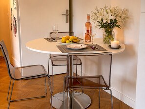 Uma mesa de jantar com cadeiras, uma vela, um vaso com flores e uma garrafa de vinho.