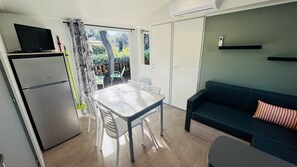 A compact living space with a kitchenette, a dining area, a sofa, and a sliding door leading to an outdoor area. - Mobile home in a magnificent estate with swimming pool in Saint-Raphaël. (Saint-Raphaël)