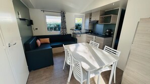 A compact kitchen with a dining table and chairs, a built-in oven, and a window with curtains. - Mobile home in a magnificent estate with swimming pool in Saint-Raphaël. (Saint-Raphaël)