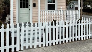 A small, single-story house with a white picket fence, a front door, and a mailbox. - Brooklyn Arts District Historic Home 1BR, 1BA (Wilmington)