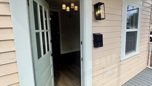 A house entrance with a number '619' above the door, a chandelier inside, and a small window on the right. - Brooklyn Arts District Historic Home 1BR, 1BA (Wilmington)