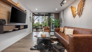 Un salon moderne doté d’un grand téléviseur à écran plat, d’un canapé en cuir et d’un tapis en peau de vache.