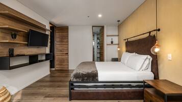 A modern bedroom with a bed, wooden shelves, a TV, and a hanging light fixture.