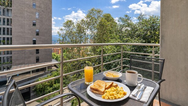A balcony with breakfast items, a clear view of buildings, and a metal railing. - Cyan 703 - 2BR in Medell n (Medellín)