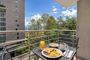 Ein Balkon mit Frühstücksangebot, freier Blick auf Gebäude und einem Metallgeländer.