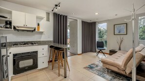 A modern kitchen with a built-in oven, a bar stool, and a dining area with a sofa and a coffee table. - Cyan 703 - 2BR in Medell n (Medellín)