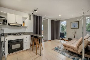 Eine moderne Küche mit Einbauofen, Barhocker und Essbereich mit Sofa und Couchtisch.