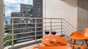 A balcony with a table and chairs, two glasses of red wine, and a view of modern buildings. - Cyan 1001 - 2BR in Medell n (Medellín)