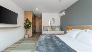 Une chambre d’hôtel moderne avec un lit, une télévision, une plante et un canapé.