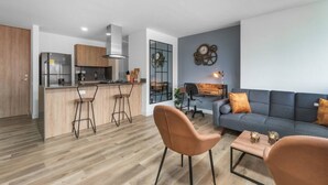 A modern kitchen with a central island, bar stools, and a dining area with a table and chairs. - Go Living Suites - 603 (Medellín)