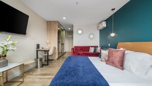 Una camera d'albergo con un letto, una scrivania, una TV e un divano rosso.