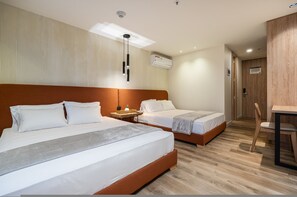 A hotel room with two beds, a desk, and a chair. - Go Living Suites - 1103 (Medellín)