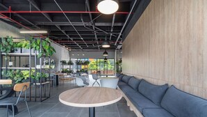A modern interior with a round table, seating area, and potted plants. - Go Living Suites - 1015 (Medellín)