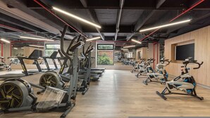 Ein Fitnessstudio mit verschiedenen Trainingsgeräten, darunter Laufbänder und Ergometer, die in Reihen angeordnet sind.