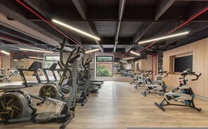 A gym with various exercise equipment, including treadmills and stationary bikes, arranged in rows. - Go Living Suites - 1417 (Medellín)