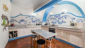 A kitchen with a tiled backsplash, a table, stools, and a microwave. - Amazing Colonial Mansion-8br-private Pool-old City (Cartagena)