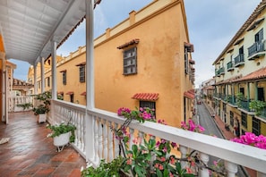 Ein überdachter Außenbereich mit Balkon, Topfpflanzen und Blick auf die Straße.