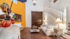 A spacious living area with a staircase, a white sofa, a coffee table, and a decorative umbrella. - Amazing Colonial Mansion-8br-private Pool-old City (Cartagena)