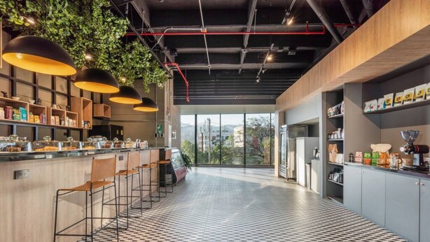 A modern kitchen with bar stools, a checkered floor, and a view through large windows. - Go Living Suites - 1407 (Medellín)
