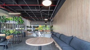 A modern interior with a round wooden table, grey sofa, and potted plants. - Go Living Suites - 1407 (Medellín)