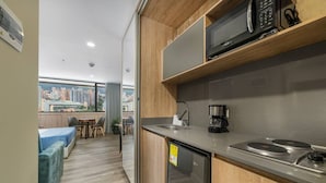 A compact kitchen with a built-in microwave, coffee maker, and a stainless steel refrigerator. - Go Living Suites - 1414 (Medellín)