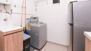 Cocina compacta con refrigerador, lavadora y pileta.