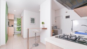 Cocina moderna con estufa a gas, un lavamanos y una encimera. Hay un taburete de bar y una planta en maceta.