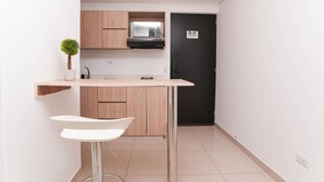 Una cocina compacta con armarios de madera, un microondas y una puerta negra.