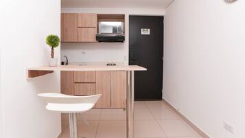 Cozinha compacta com armários de madeira, micro-ondas e porta preta.