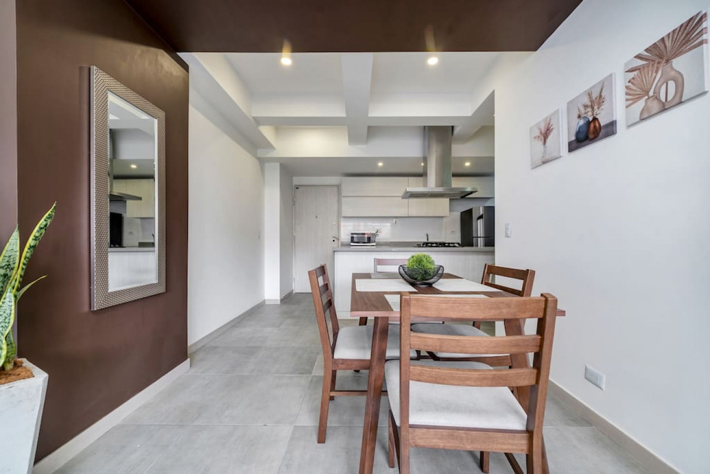Una cuina moderna amb armaris blancs, una illa central i una zona de menjador amb cadires i taula de fusta.