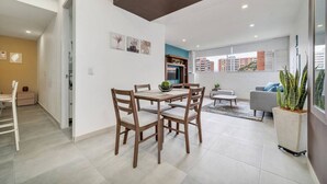 Una sala de estar moderna con comedor, un sofá, una mesa de centro y una planta en maceta.