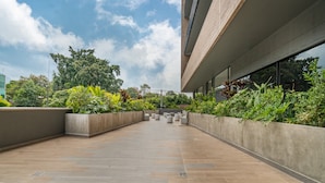 A modern building with a flat roof terrace, concrete planters with greenery, and a clear sky. - Go Living Suites - 1315 (Medellín)
