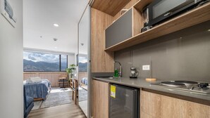A compact kitchen with a built-in microwave, a small refrigerator, and a sink. - Go Living Suites - 1315 (Medellín)