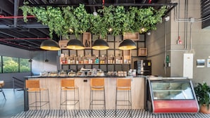 A modern bar area with a checkered floor, wooden bar counter, and pendant lighting. - Go Living Suites - 1315 (Medellín)