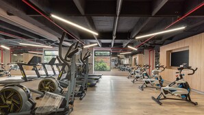A gym with multiple exercise machines, wooden walls, and large windows. - Go Living Suites - 1315 (Medellín)